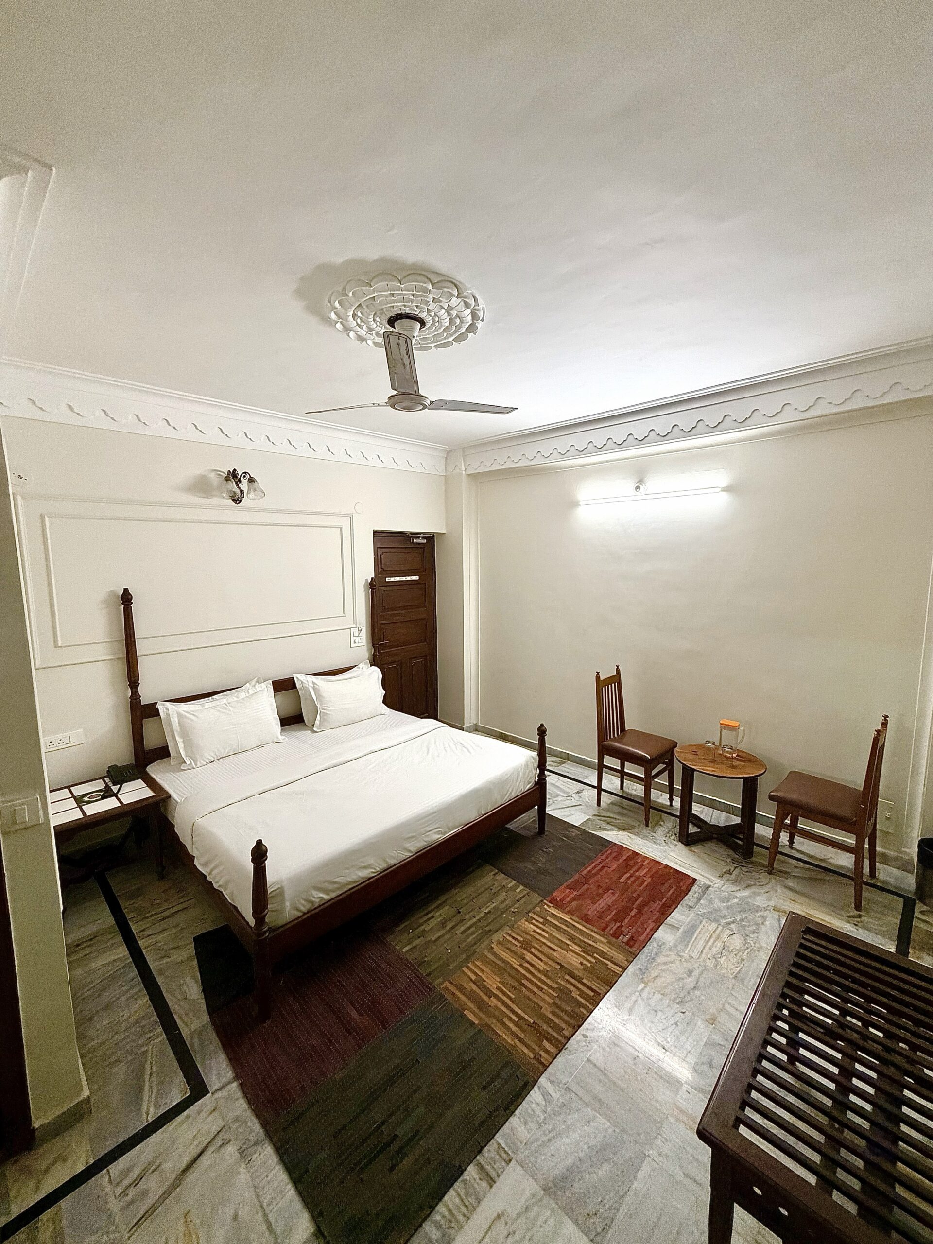 Super Deluxe Room at Hotel Royale Plazo Jodhpur with large wooden bed, seating area, modern lighting and marble flooring