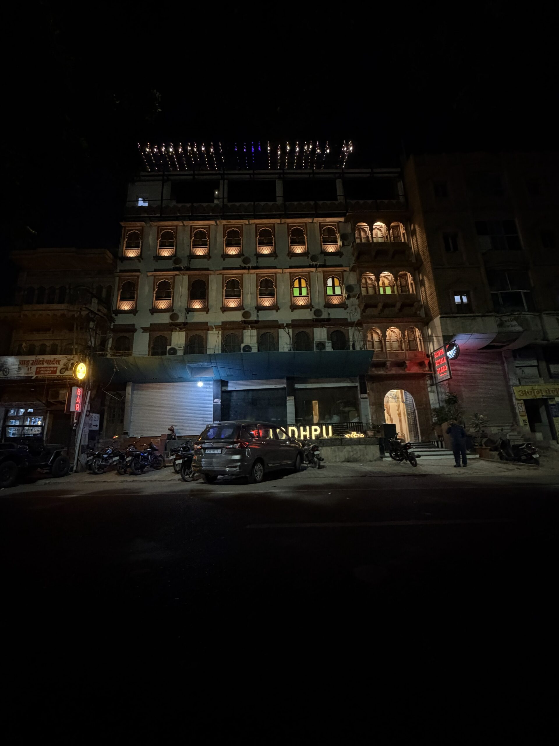 Night view exterior of Hotel Royale Plazo in Jodhpur with illuminated heritage-style architecture and parking area